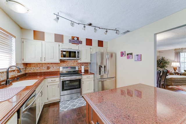 kitchen with sink, dark hardwood / wood-style flooring, stainless steel appliances, white cabinets, and decorative backsplash