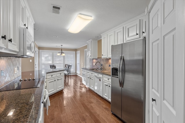 kitchen featuring dark wood-type flooring, sink, decorative light fixtures, white cabinetry, and white appliances