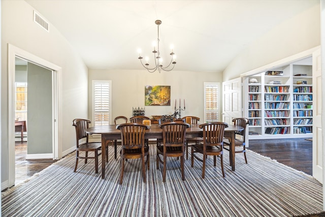 dining room with dark wood-type flooring, a notable chandelier, and lofted ceiling