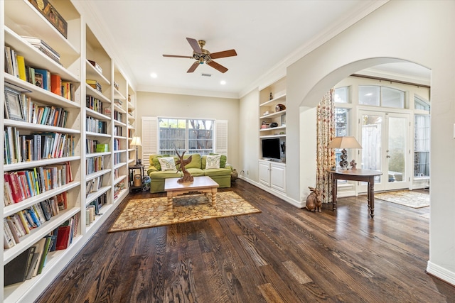 sitting room with french doors, dark wood-type flooring, ornamental molding, built in shelves, and ceiling fan