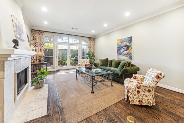 living room featuring a tile fireplace, crown molding, and light hardwood / wood-style floors