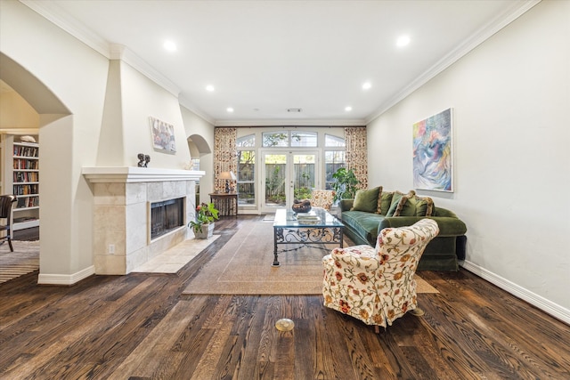 living room with french doors, crown molding, dark hardwood / wood-style flooring, and a tile fireplace