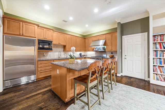 kitchen featuring built in appliances, backsplash, dark hardwood / wood-style floors, and a kitchen island