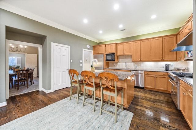 kitchen featuring a kitchen island, dark wood-type flooring, built in appliances, light stone countertops, and a kitchen bar