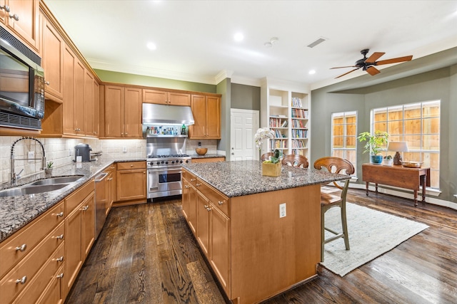 kitchen with a kitchen island, dark hardwood / wood-style floors, dark stone countertops, stainless steel appliances, and sink