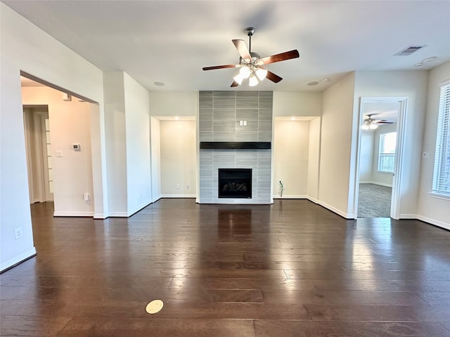 unfurnished living room featuring ceiling fan, a fireplace, and dark hardwood / wood-style flooring