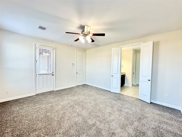 unfurnished bedroom with ensuite bath, light colored carpet, and ceiling fan