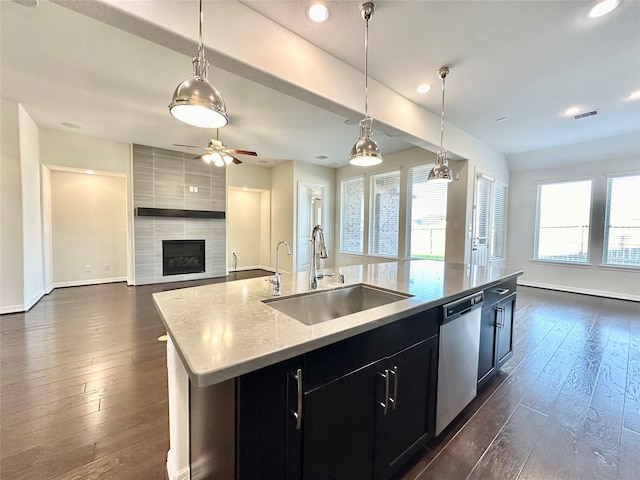 kitchen featuring a kitchen island with sink, stainless steel dishwasher, dark hardwood / wood-style floors, pendant lighting, and sink