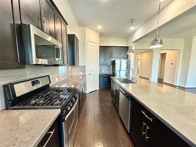 kitchen featuring tasteful backsplash, appliances with stainless steel finishes, sink, decorative light fixtures, and dark wood-type flooring