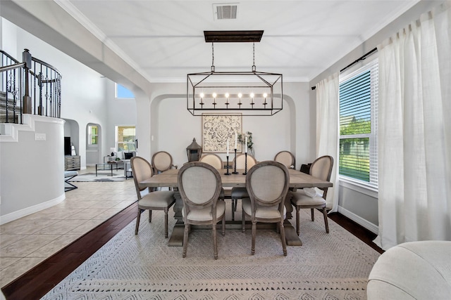 dining space with light hardwood / wood-style flooring, ornamental molding, and a notable chandelier