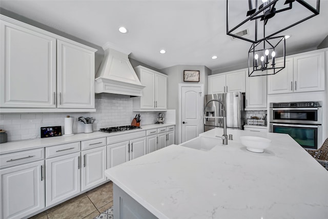 kitchen featuring decorative backsplash, custom exhaust hood, stainless steel appliances, pendant lighting, and white cabinets