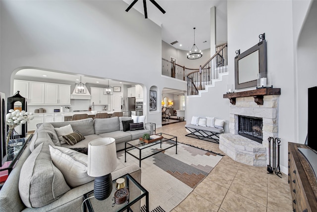 living room with a fireplace, a towering ceiling, a notable chandelier, and light tile patterned flooring