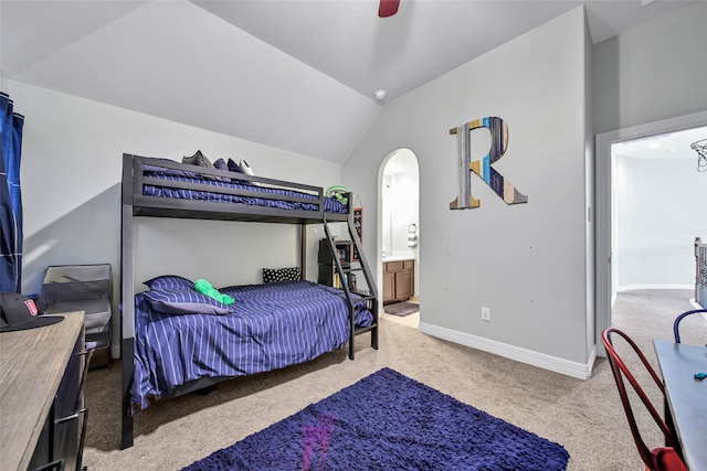 bedroom featuring ceiling fan, light colored carpet, ensuite bathroom, and vaulted ceiling