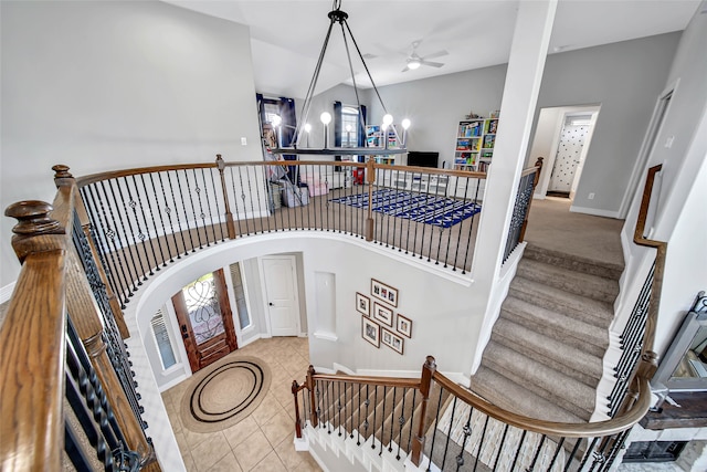 staircase with tile patterned floors, ceiling fan with notable chandelier, and vaulted ceiling