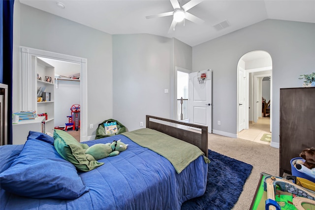 bedroom featuring light carpet, a walk in closet, ceiling fan, a closet, and lofted ceiling