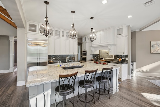 kitchen with white cabinets, stainless steel appliances, hanging light fixtures, and dark hardwood / wood-style floors