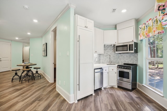 kitchen with white cabinetry, sink, appliances with stainless steel finishes, dark hardwood / wood-style floors, and crown molding