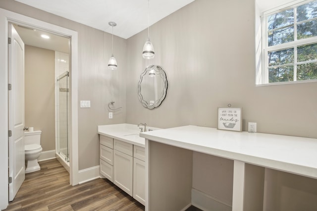 bathroom with hardwood / wood-style flooring, a shower with shower door, vanity, and toilet