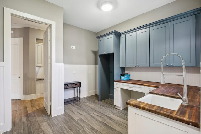 38134 Cascade Ct, Magnolia, TX 77354 - kitchen with wooden counters, a wainscoted wall, light wood-style floors, and blue cabinetry