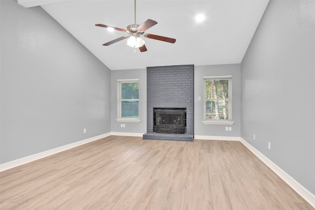 unfurnished living room featuring a brick fireplace, light wood-type flooring, vaulted ceiling, and ceiling fan