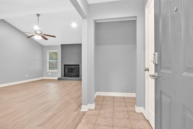 unfurnished living room with ceiling fan, light wood-type flooring, and a brick fireplace