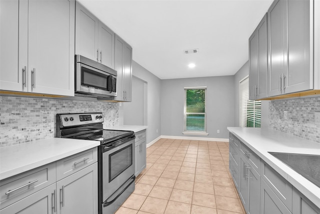 kitchen with light tile patterned floors, stainless steel appliances, and tasteful backsplash