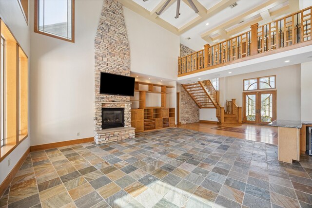 unfurnished living room with a towering ceiling, french doors, beamed ceiling, and a fireplace