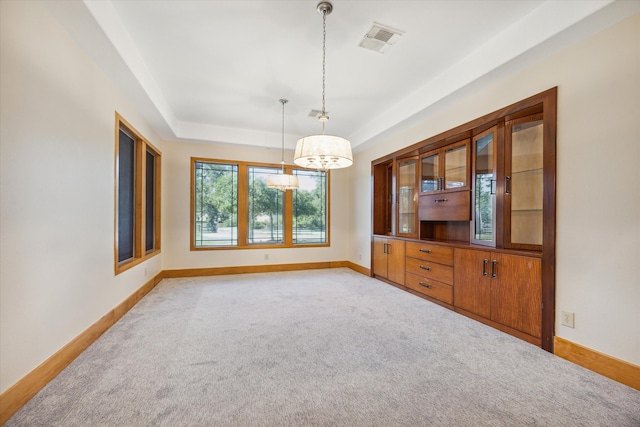 carpeted empty room featuring a notable chandelier