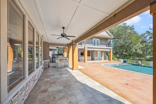 view of patio with a balcony, area for grilling, a water view, and ceiling fan