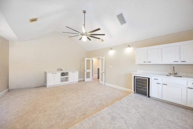 bar featuring sink, white cabinetry, light carpet, lofted ceiling, and beverage cooler