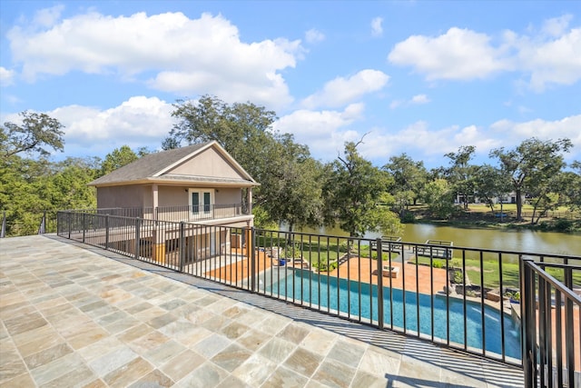 view of swimming pool featuring a water view and a patio