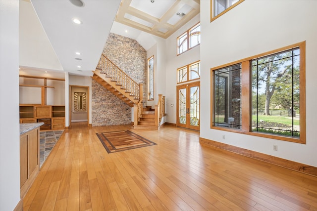 interior space featuring brick wall, a high ceiling, light hardwood / wood-style flooring, and french doors