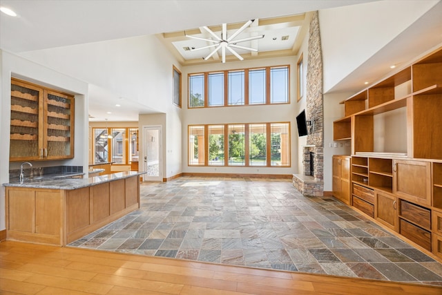 unfurnished living room with light hardwood / wood-style flooring, a high ceiling, a fireplace, a notable chandelier, and sink