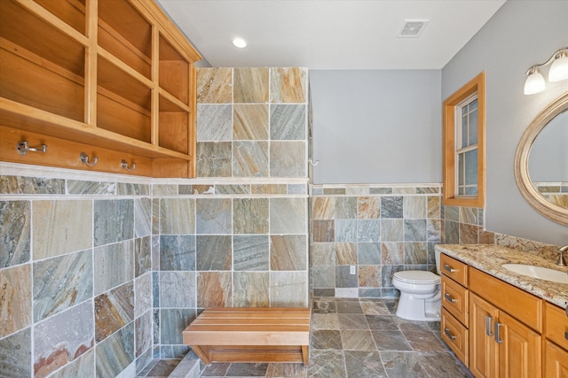 bathroom with tile walls, vanity, and toilet