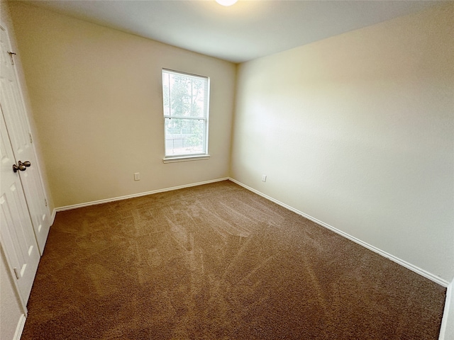 spare room featuring dark colored carpet