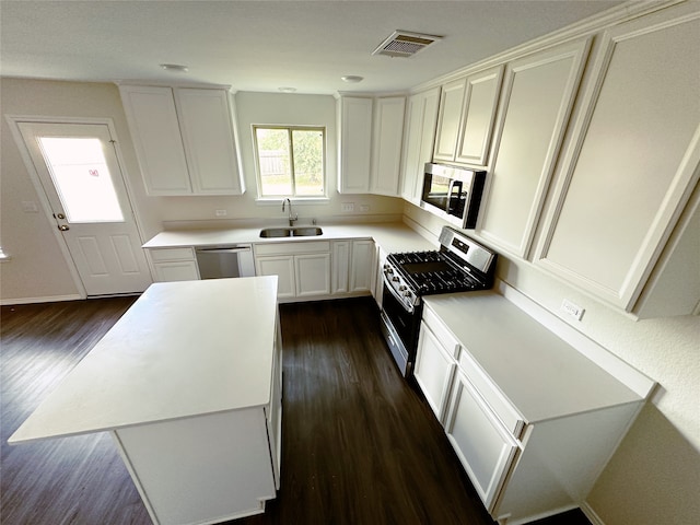 kitchen with dark wood-type flooring, stainless steel appliances, sink, a center island, and white cabinetry