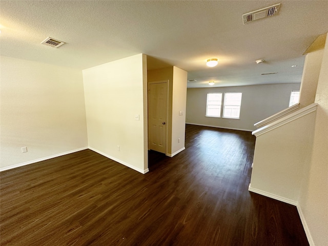 spare room with a textured ceiling and dark hardwood / wood-style flooring