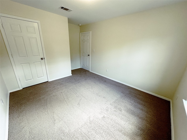 unfurnished bedroom with dark carpet and a closet