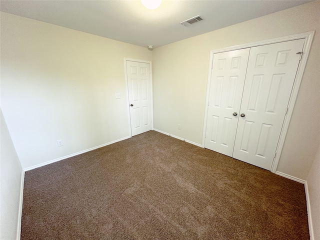 unfurnished bedroom featuring dark carpet and a closet