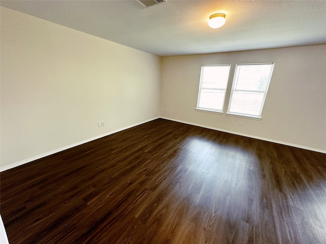 empty room featuring a textured ceiling and dark hardwood / wood-style floors