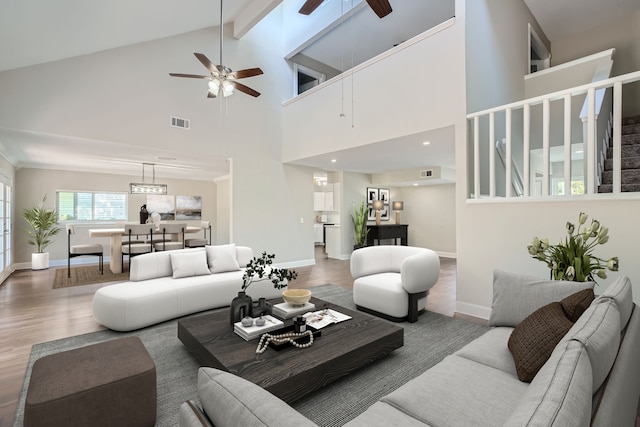 living room with ceiling fan, high vaulted ceiling, wood-type flooring, and beam ceiling