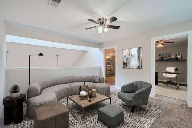 living room with a textured ceiling, carpet flooring, and ceiling fan