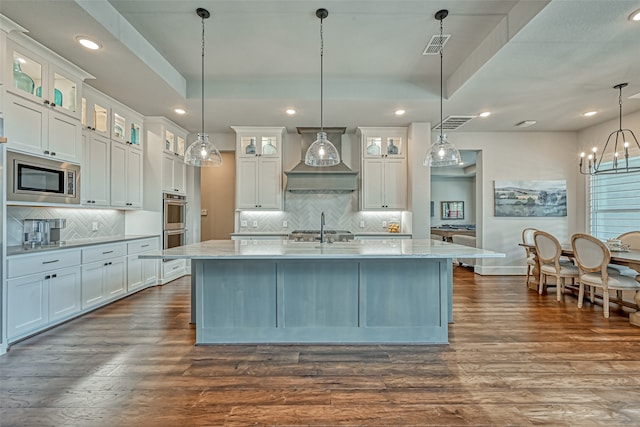 kitchen with tasteful backsplash, hanging light fixtures, stainless steel appliances, white cabinets, and dark hardwood / wood-style floors