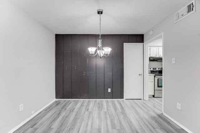 unfurnished dining area with a notable chandelier and light wood-type flooring