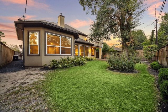 back house at dusk with a lawn