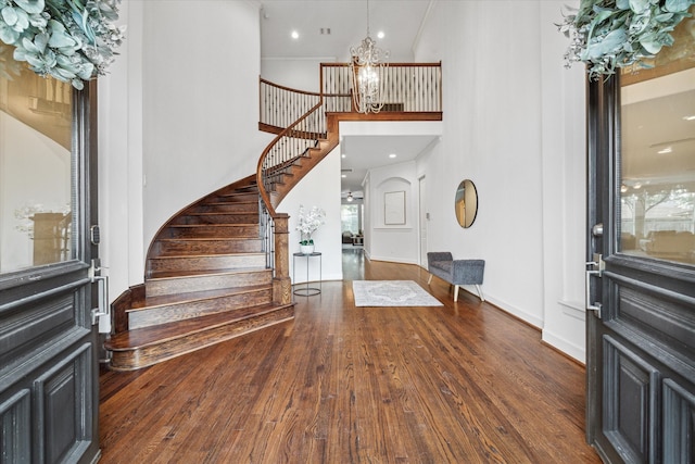 foyer entrance with a towering ceiling, an inviting chandelier, and dark hardwood / wood-style floors