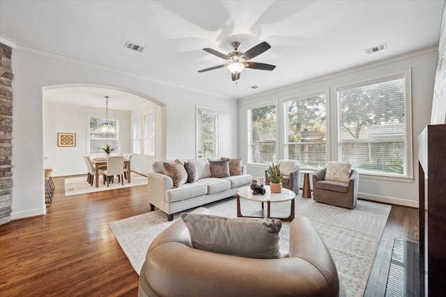 living room featuring ornamental molding, dark wood-type flooring, and ceiling fan with notable chandelier