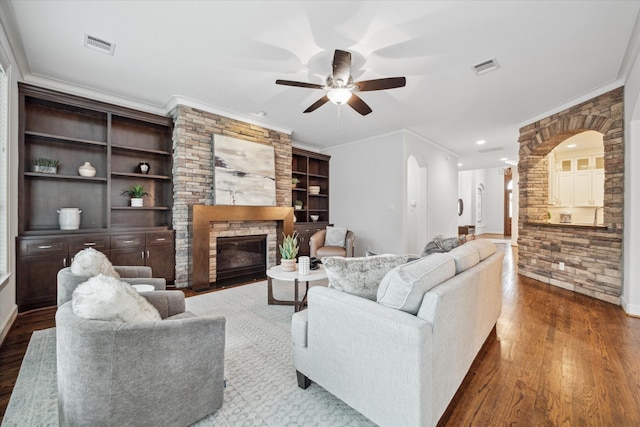 living room featuring ceiling fan, hardwood / wood-style flooring, ornamental molding, and a fireplace