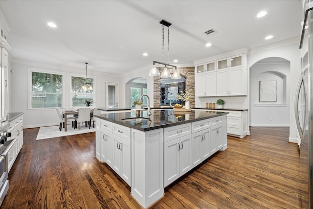 kitchen featuring sink, an island with sink, pendant lighting, and white cabinets