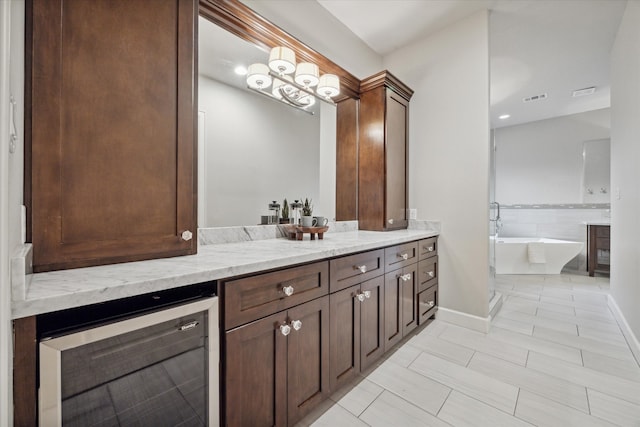 bathroom featuring wine cooler, vanity, and a relaxing tiled tub